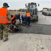 Жол жөндеушілер теміржол рельсі үстінен асфальт төсеп тастаған